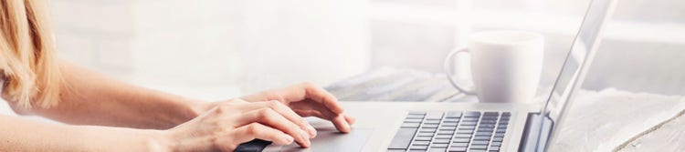 person using computer with mug on desk