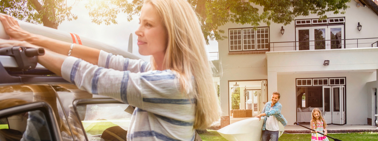 actor portrayal of woman tying a kayak on the roof of the car while a man holds a kayak and little girl holds a paddle